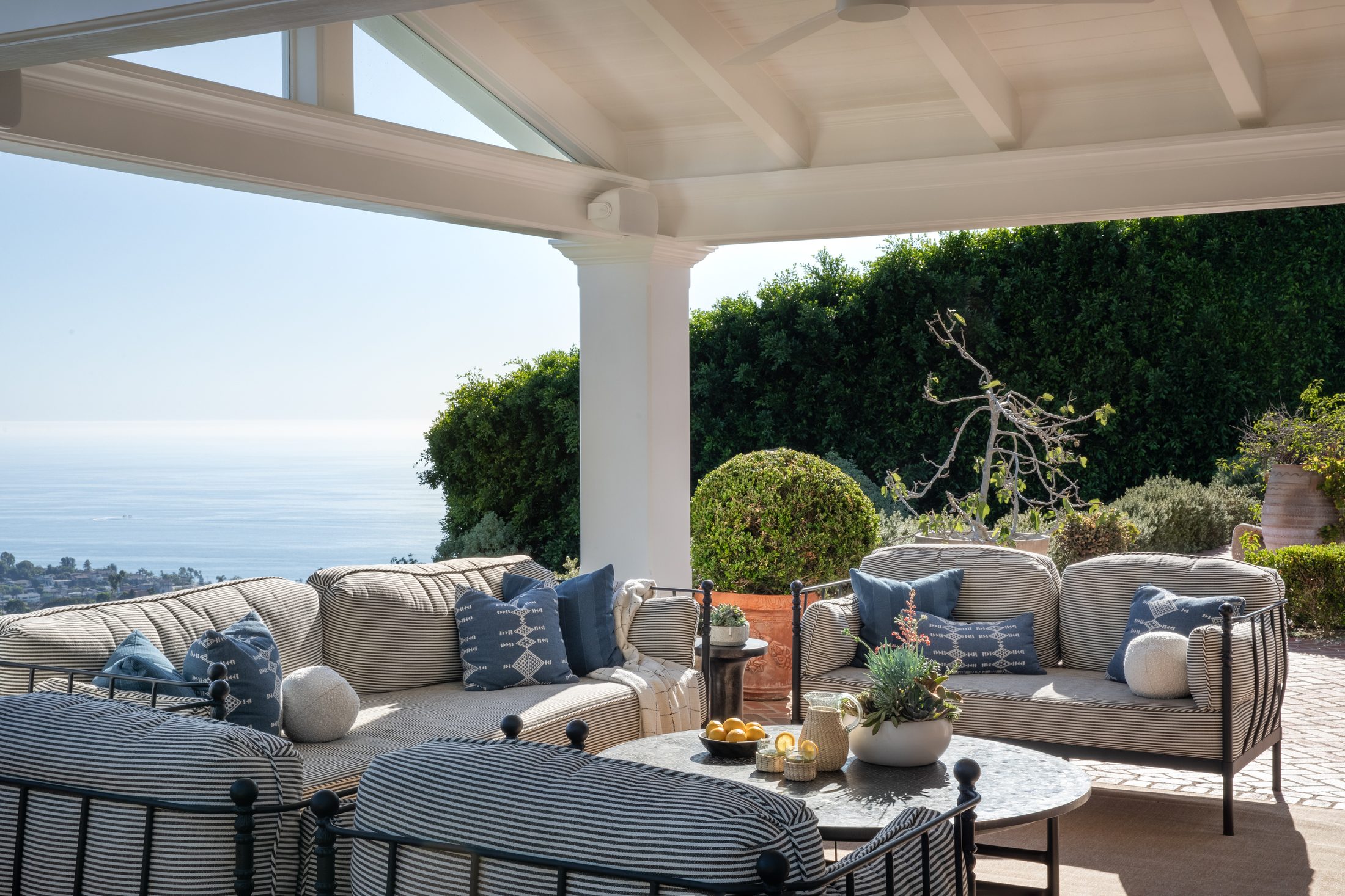 Covered ocean-view loggia with striped upholstery and rattan accents